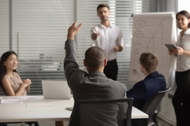 Erkek işçi, ofis brifinginde soru sorar.