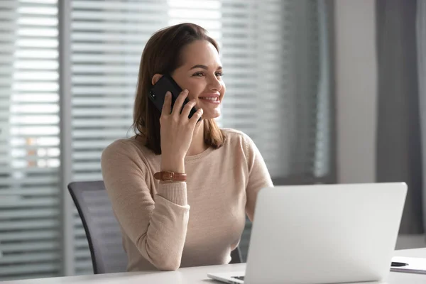 Щаслива жінка співробітниця розмовляє на мобільному телефоні на робочому місці — стокове фото