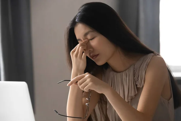 Tired Asian employee suffering from headache at work — Stock Photo, Image