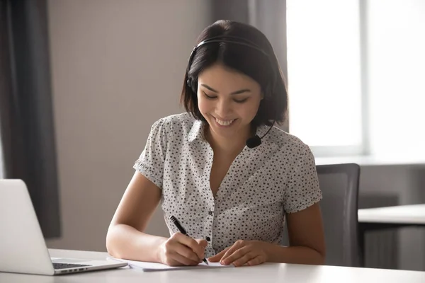 Gelukkig vrouw in headset maken notities kijken online cursus — Stockfoto