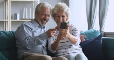 Happy middle aged family having fun, making selfie on smartphone.