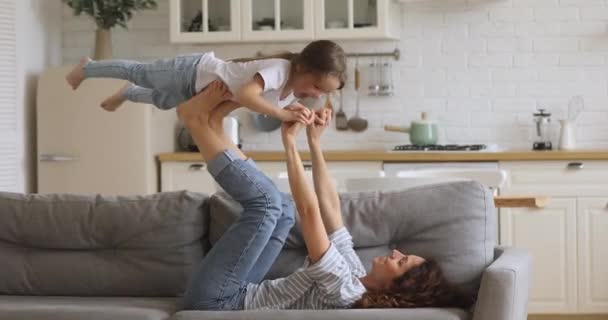 Щаслива приваблива молода мати піднімає задоволену маленьку доньку . — стокове відео
