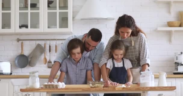 Smiling couple teaching children siblings flattening dough with rolling pins. — Stock Video