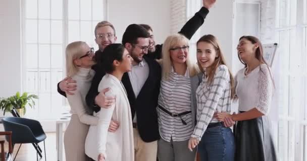 Líder femenina mayor une a jóvenes empleados abrazándose riendo en la oficina — Vídeos de Stock