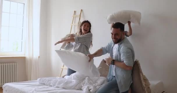 Alegre pareja casada luchando almohadas con niños pequeños felices . — Vídeo de stock