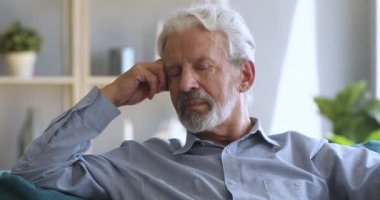 Thoughtful older man looking at camera, hearing good news.