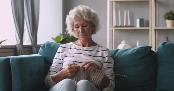 Mírumilovný středního věku v důchodu chraptivá žena plete vlněnou šálu. — Stock video