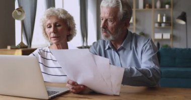 Serious older couple managing family budget at home.