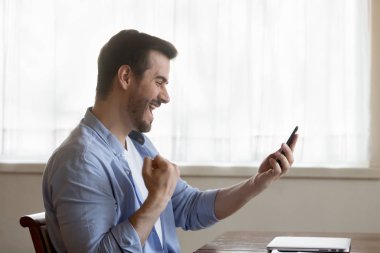 Overjoyed young man triumph with good cellphone message