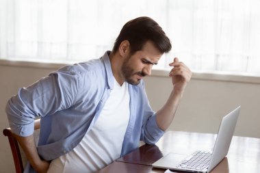 Unwell young man suffer from working in incorrect posture
