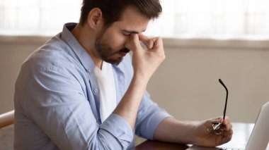 Tired man take off glasses suffering from headache
