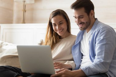 Happy young couple relax at home using laptop