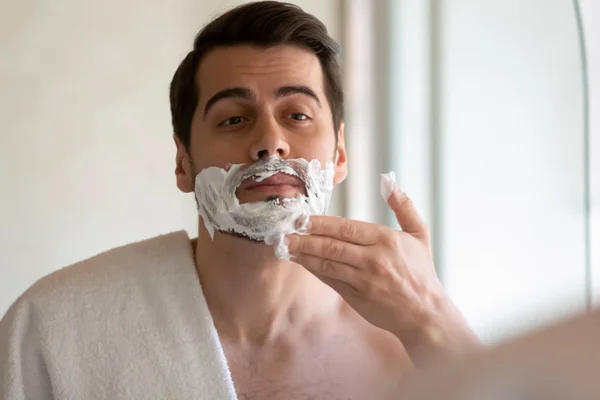 Young man look in mirror shaving in bathroom — Stock Photo, Image