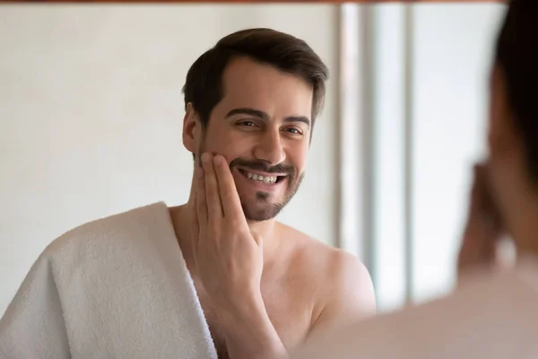 Smiling millennial man apply face lotion after shaving — Stock Photo, Image