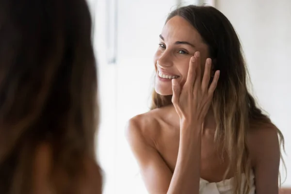 Smiling girl look in mirror do skincare facial routine — ストック写真