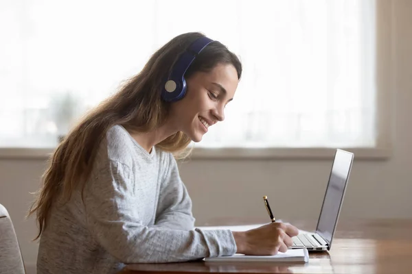 Jovem sorridente em fones de ouvido estudando no laptop — Fotografia de Stock