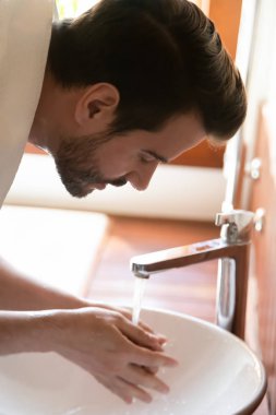 Caucasian man wash face do morning routine in bathroom