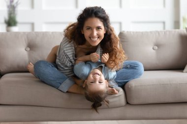 Happy attractive young mom tickling little preschool daughter.