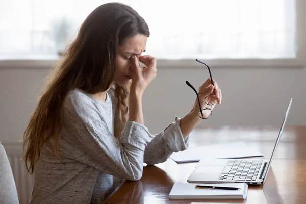 Tired young woman massage eyes suffering from headache