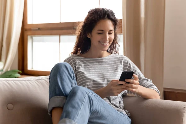 Улыбающаяся молодая леди, использующая мобильные приложения дома . — стоковое фото