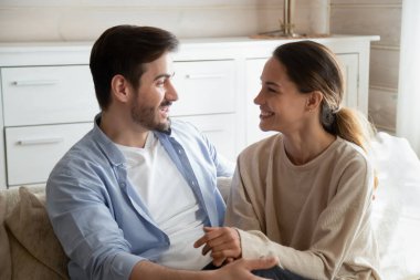 Happy young couple relax on couch talking at home