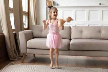 Energetic small child girl dancing alone in living room.