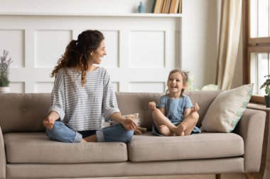 Happy mommy practicing yoga exercised with small child.
