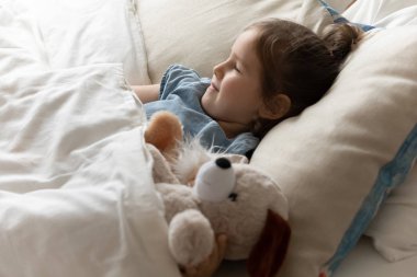 Happy little preschool child daughter sleeping in bed.