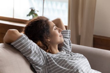Peaceful tranquil attractive young woman taking pause break on couch.