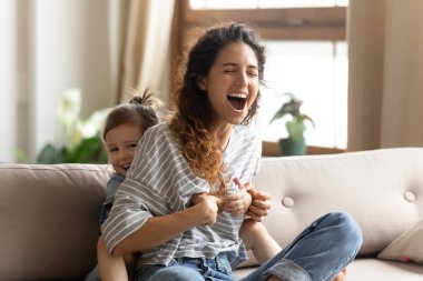 Playful little child girl tickling laughing woman.