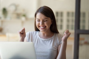 Excited young woman triumph reading good news online
