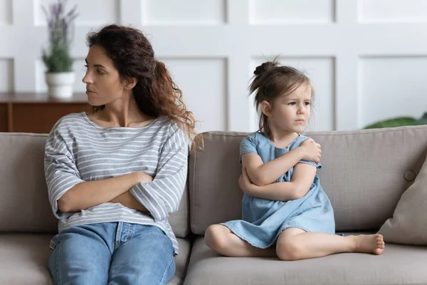 Stressed young mother ignoring offended little preschool daughter.