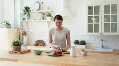 Happy young woman cooking in modern design kitchen