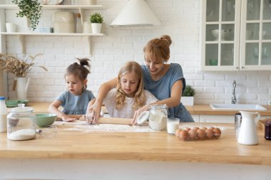 Young mom and little daughters baking at home