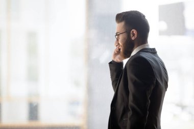 Bearded arab businessman negotiating distantly talking on phone in office