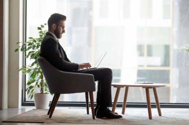 Arab businessman sitting in office lobby working on laptop