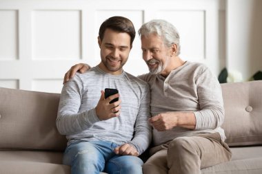 Young man showing funny video on smartphone to happy father.