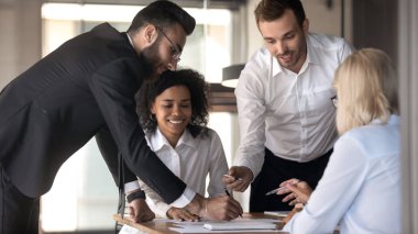 Diverse colleagues managing company finances do paperwork at group meeting