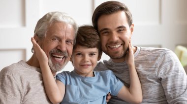 Happy three generations affectionate family looking at camera.