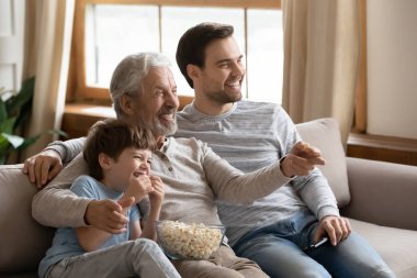 Happy three generations male family watching football championship match.