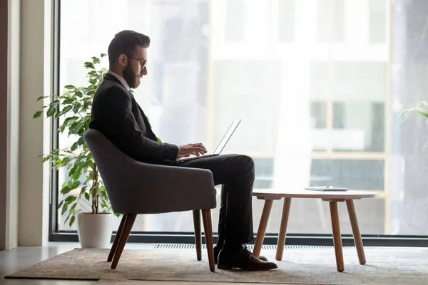 Arab businessman sitting in office lobby working on laptop — 图库照片