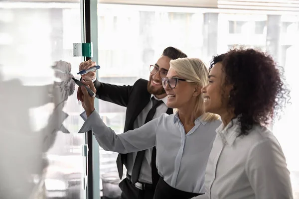 Three diverse entrepreneurs working on business strategy using white board — Stockfoto