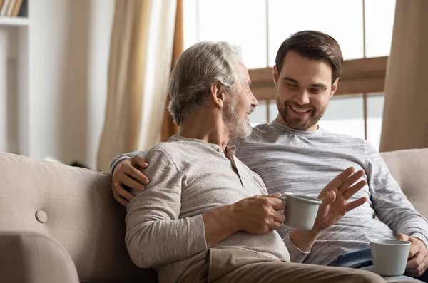 Joyful two generations family sharing news with cup of tea.