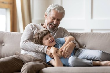 Excited older senior grandfather tickling laughing kid boy.
