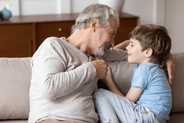 Pleasant middle aged man having sincere trustful conversation with grandchild.