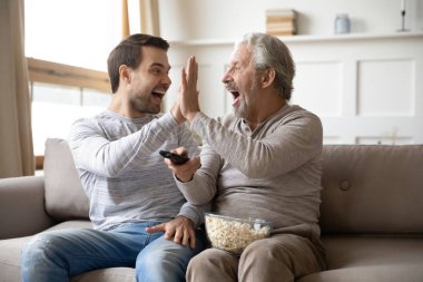 Happy young man giving high five to overjoyed father.