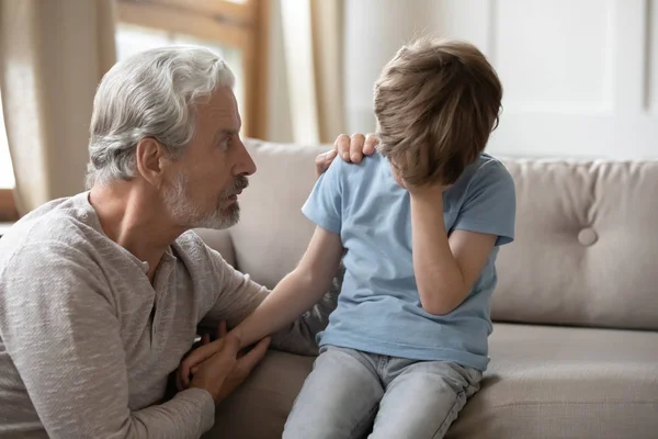 Worried middle aged hoary man supporting little offended grandchild. — Stock Photo, Image