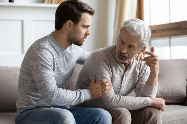 Young stressed man comforting irritated mature old father. — 图库照片