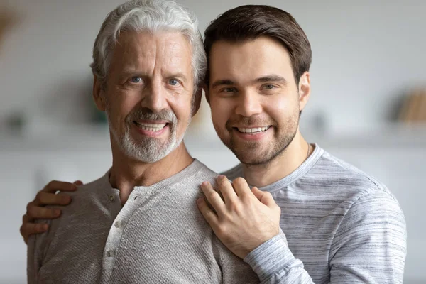 Pleasant young man embracing mature old daddy.