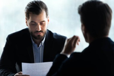 Close up serious businessman reading cv new job candidate.